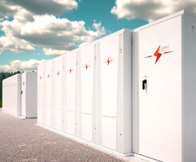 A row of white metal cabinets containing commercial-scale battery systems