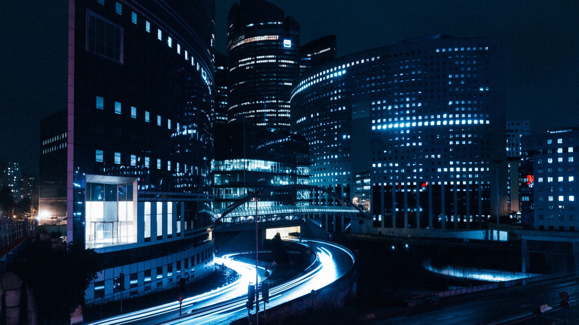 modern city buildings illuminated at night with dynamic light trails